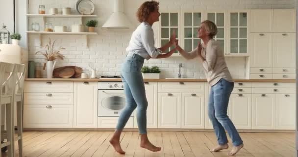 Молода жінка танцює на кухні з літньою матір'ю — стокове відео