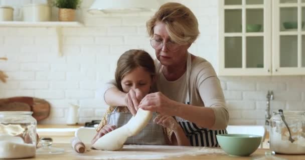 Fürsorgliche Oma lehrt ihre kleine Enkelin den Teig ausrollen — Stockvideo