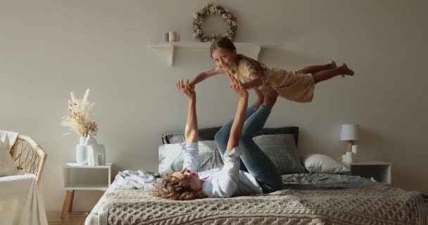 Mujer joven acostada en la cama jugar con su hija pequeña — Vídeos de Stock
