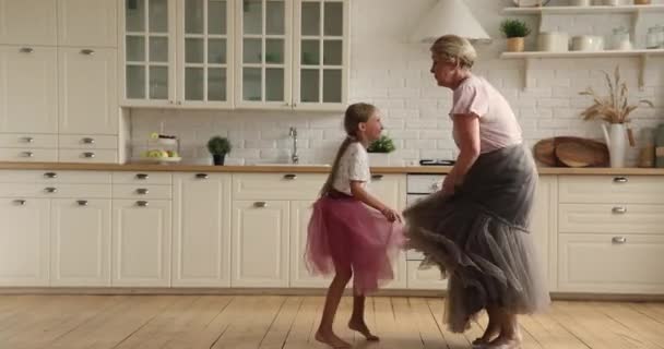 Active 60s oma dans in de moderne keuken met kleine kleindochter — Stockvideo