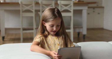 Tablet kullanan küçük kız evde eğleniyor.