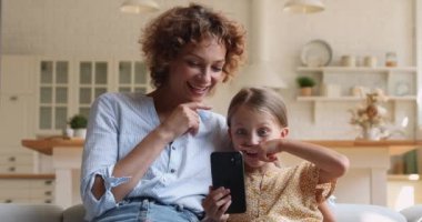 Anne ve kızı akıllı telefondan mobil uygulama kullanarak eğleniyorlar.