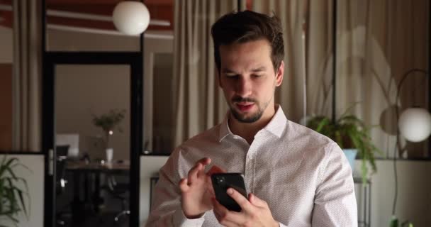 Орієнтований щасливий молодий іспаномовний бізнесмен, використовуючи мобільні додатки в офісі . — стокове відео