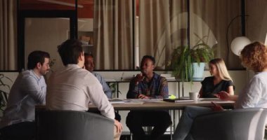 İlgilenen çok ırklı takım arkadaşları ofiste çalışma meselelerini tartışıyorlar..