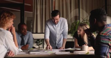 Genç erkek takım lideri iş arkadaşlarına pazarlama araştırma sonuçlarını açıklıyor.