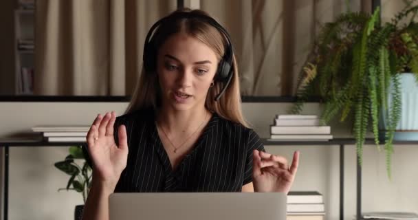 Fókuszált fiatal női menedzser fülhallgatóban videohívással. — Stock videók