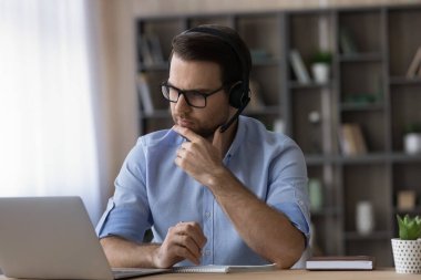 Kulaklık takan düşünceli adam internette çalışıyor.