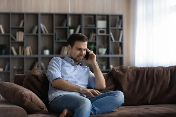 Молодий кавказький чоловік розмовляє вдома по мобільному. — стокове фото