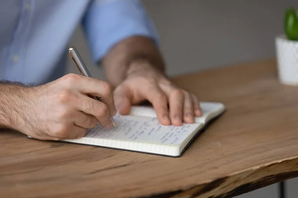 Close up of man write in notepad at desk