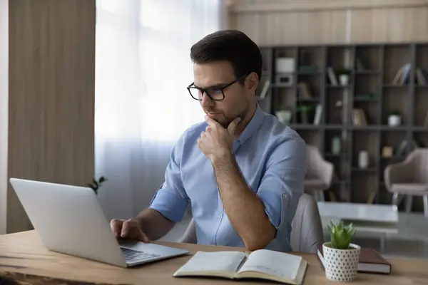 Trabajo masculino pensativo en el ordenador portátil haciendo notas —  Fotos de Stock