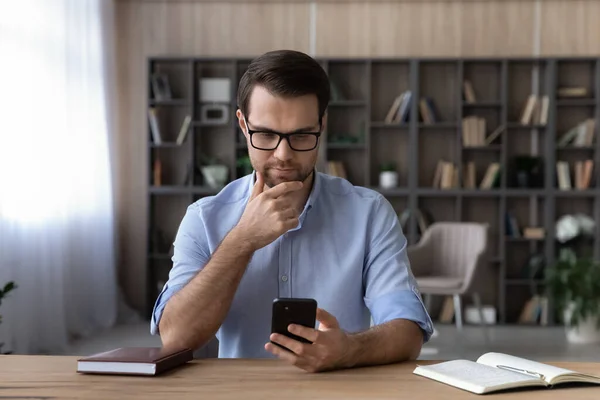 Pensive Caucasian man use cellphone browsing internet