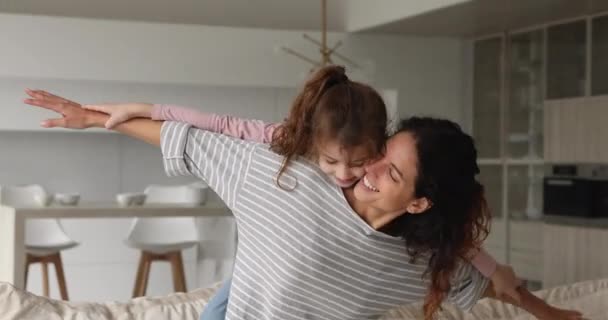 Mulher piggyback filha espalhar braços como asas de avião jogar interior — Vídeo de Stock