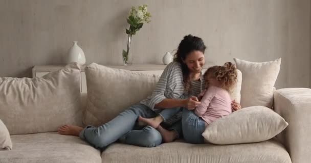 Mulher alegre animada jogar no sofá com a pequena filha — Vídeo de Stock