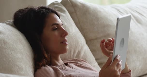 Woman lean on sofa cushions relaxing with digital computer tablet — Stock Video