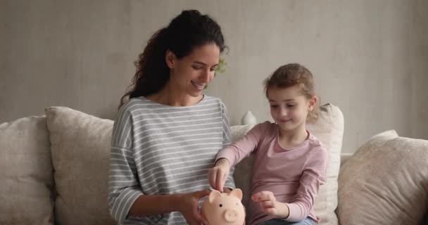 Thrifty menina coloca moedas em porquinho banco — Vídeo de Stock