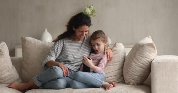 Mädchen und Mutter ruhen sich drinnen aus und haben Spaß mit mobiler Anwendung — Stockvideo