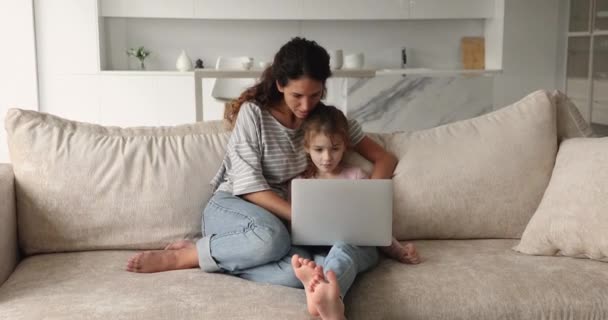 Μητέρα και μικρή κόρη κάθονται στον καναπέ με το laptop — Αρχείο Βίντεο