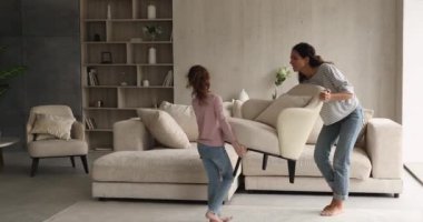 Anne ve küçük kız oturma odalarındaki mobilyaları yeniden düzenliyorlar.