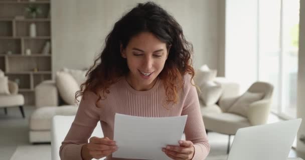 Молода жінка сидить в приміщенні читати лист відчуває себе щасливим святкувати успіх — стокове відео