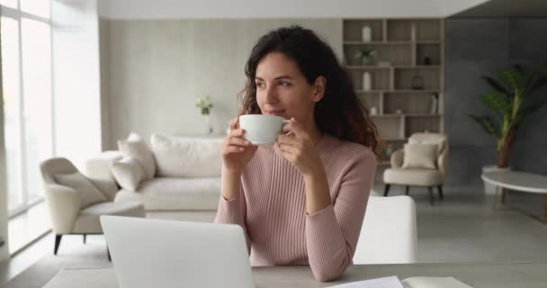 机の上に座りながらコーヒーを飲む平和な女性 — ストック動画