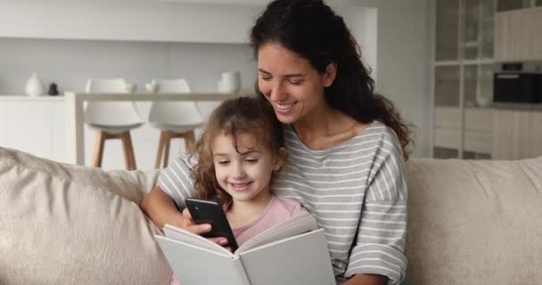 Familia distraída de leer un libro divertirse con el teléfono inteligente — Vídeo de stock