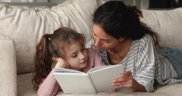 Junge liebevolle Mutter liest ihrer Vorschultochter ein Buch vor — Stockvideo