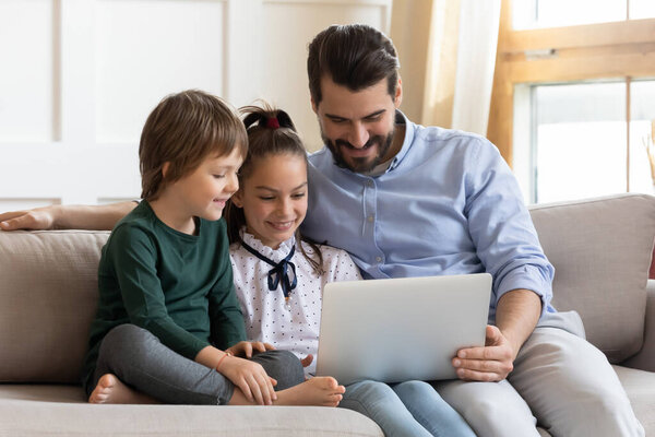 Happy dad and two kids browse laptop together