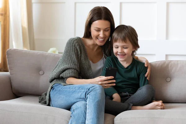 Uśmiechnięta matka i mały syn grać online na smartfonie — Zdjęcie stockowe