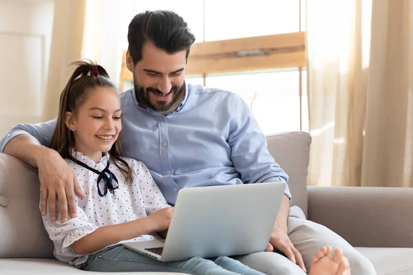 Papá feliz y la pequeña hija utilizan el ordenador portátil en casa —  Fotos de Stock