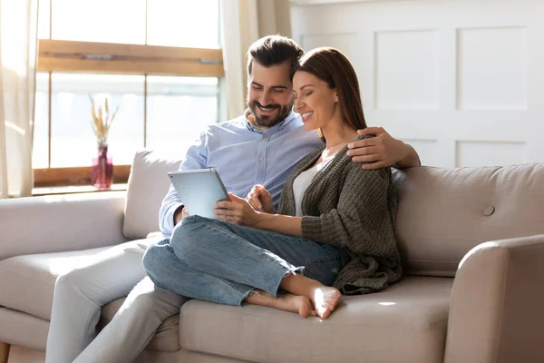 Glückliches Paar entspannt auf Sofa mit Tablet zusammen — Stockfoto