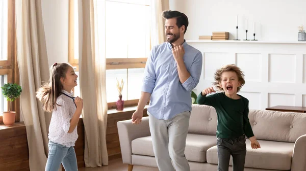 Överlycklig far och två barn dansar tillsammans hemma — Stockfoto