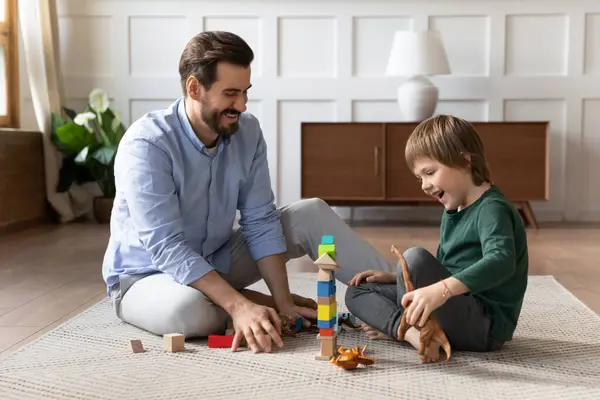 Leende far och liten son leker tillsammans med leksaker — Stockfoto