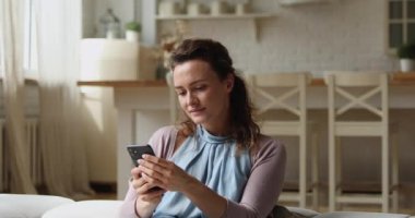 Evde akıllı telefon kullanan hayalperest, rahat bir kadın..