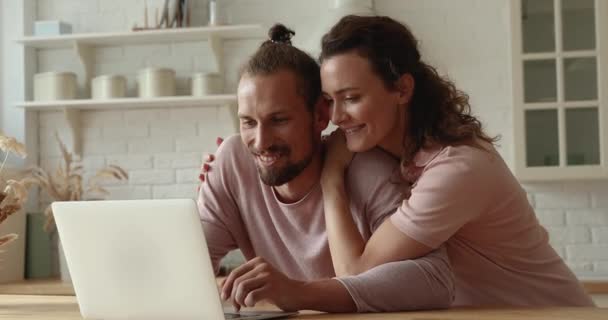 Glad bindning tillgiven ung par med hjälp av dator hemma. — Stockvideo
