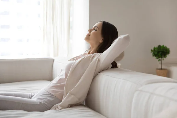 Wanita milenial yang bahagia bersantai di sofa, menghirup udara dingin — Stok Foto
