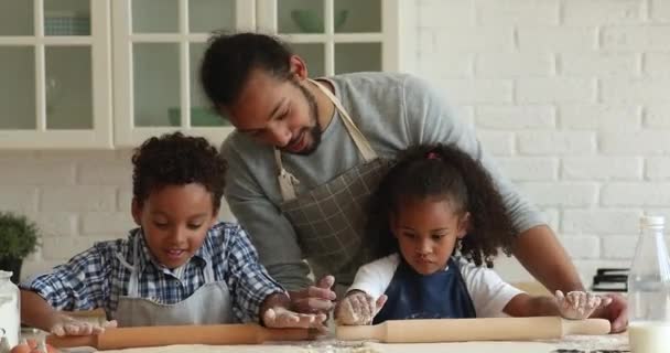 Smiling young caring afro father teaching little children cooking. — Stock Video