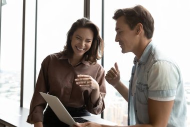 Gülümseyen çeşitli meslektaşlar bilgisayar üzerinde çalışırken eğleniyor