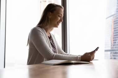 Gülümseyen kadının cep telefonunda webcam zoom çağrısı var.