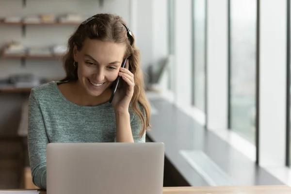 Sonriente mujer empleado trabajo en portátil hablar en el teléfono celular — Foto de Stock