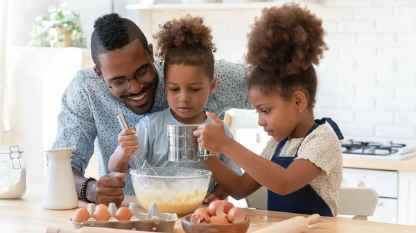 Happy dad teaching two cute preschooler kids to bake — Stock Photo, Image