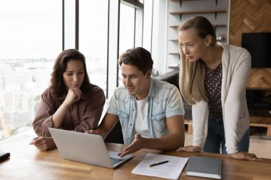 Çeşitli meslektaşlar ofiste dizüstü bilgisayarda birlikte çalışıyorlar.