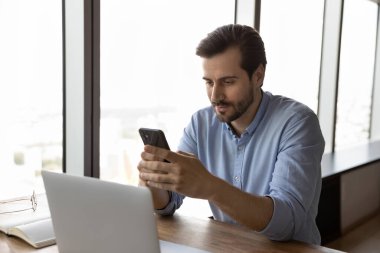 Genç erkek çalışan modern akıllı telefon aygıtı kullanıyor