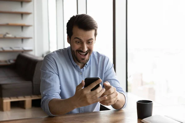 Excited young man shocked by good news on smartphone — Stock Photo, Image