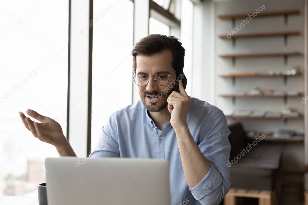 Young businessman work on laptop talk on smartphone