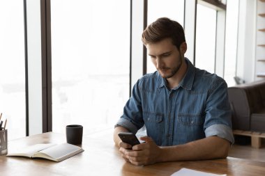 Genç beyaz adam işyerinde cep telefonu kullanıyor.