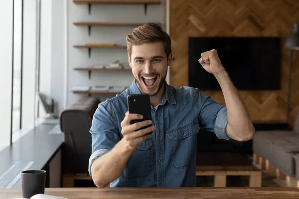 Excited man triumph with good news on smartphone