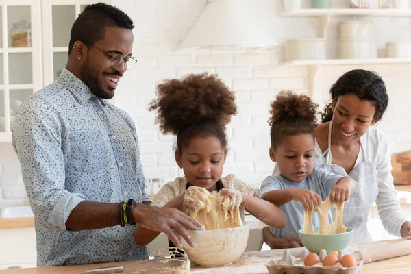 有趣的非裔美国父母帮助可爱的孩子揉搓面团 — 图库照片