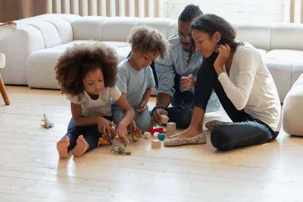 Afroamerikanische Eltern und zwei Vorschulkinder spielen Spielzeug — Stockfoto