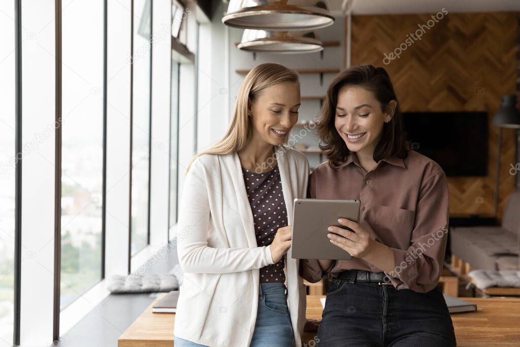 Smiling women employees work on tablet in office