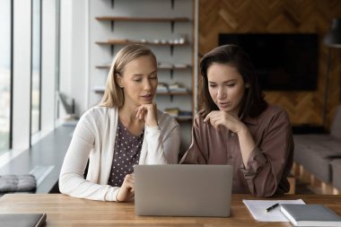Dizüstü bilgisayardaki kadın meslektaşlar ofiste beyin fırtınası yapıyor.